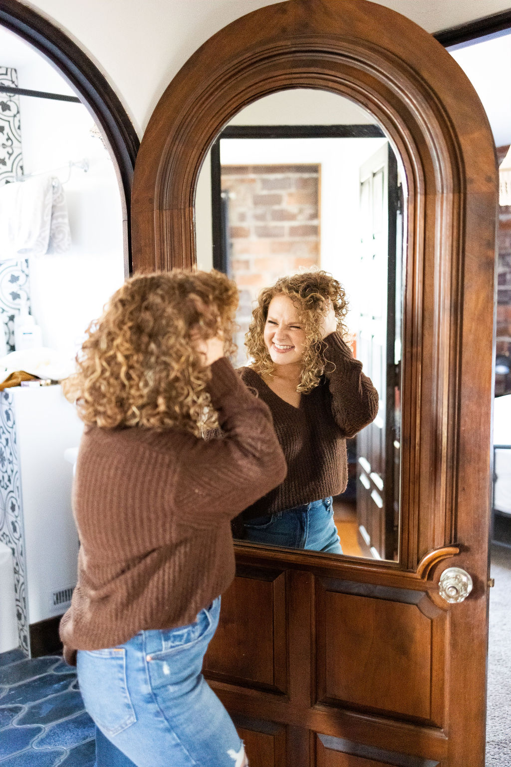 woman fixing hair in mirror