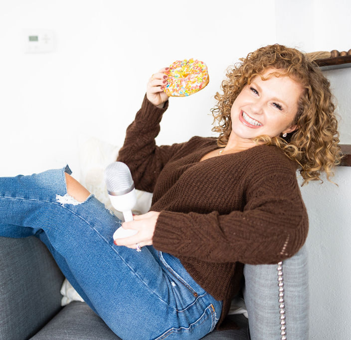 female holding donut and microphone