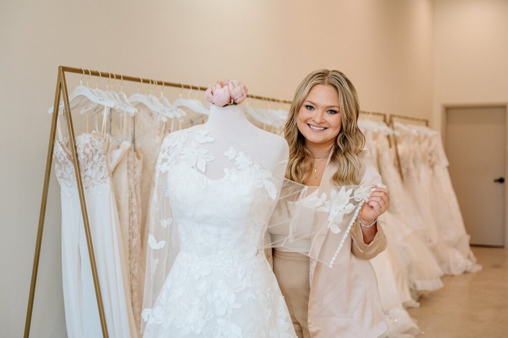Erynn putting a wedding gown on a mannequin at Embody Bridal