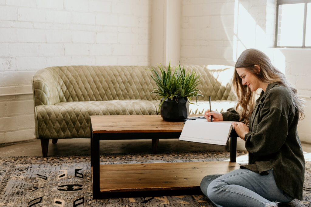 Strategic brand photos in Iowa studio with model posing by table and couch
