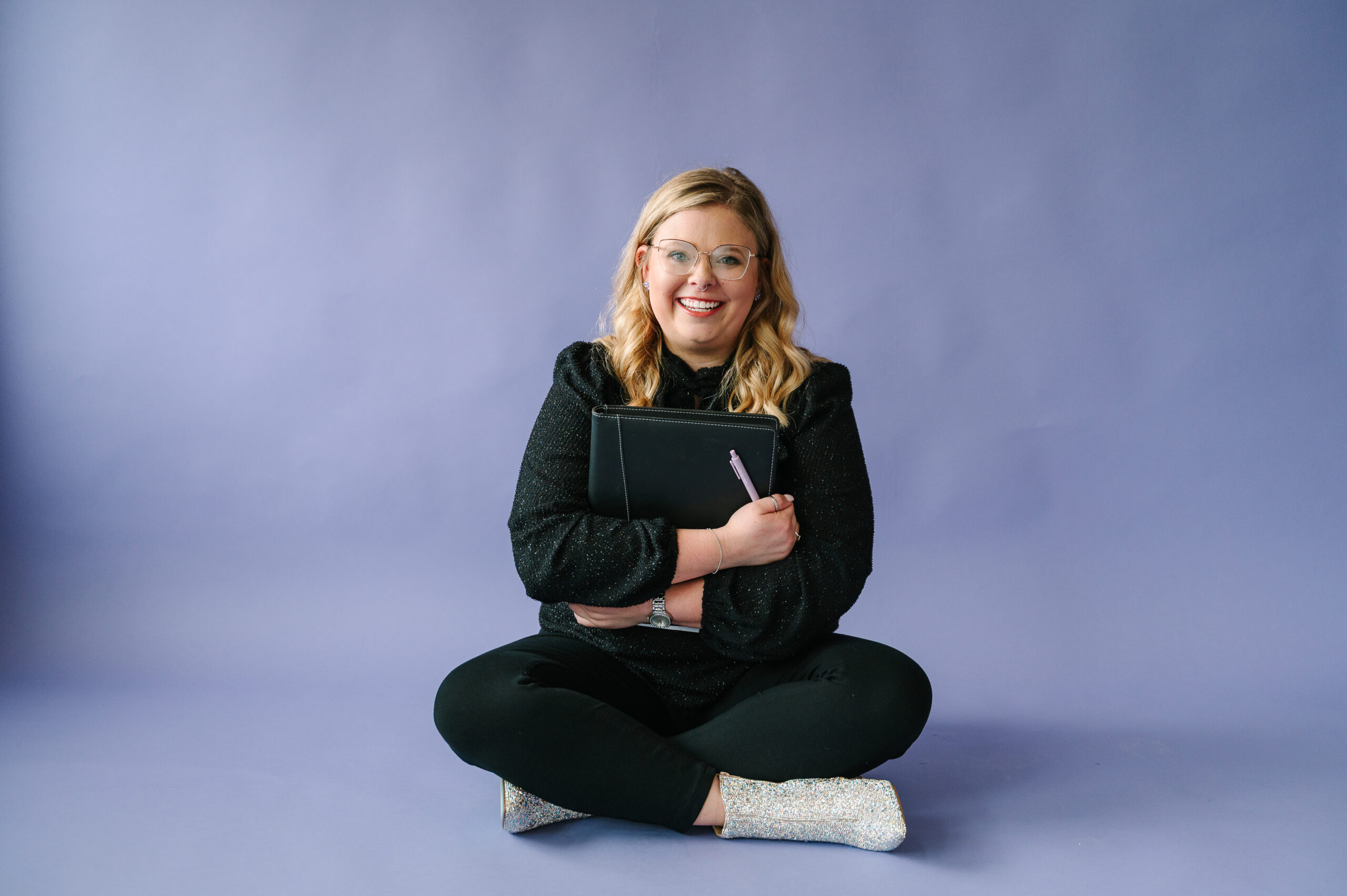 Iowa wealth management brand photo in black work outfit and purple wall