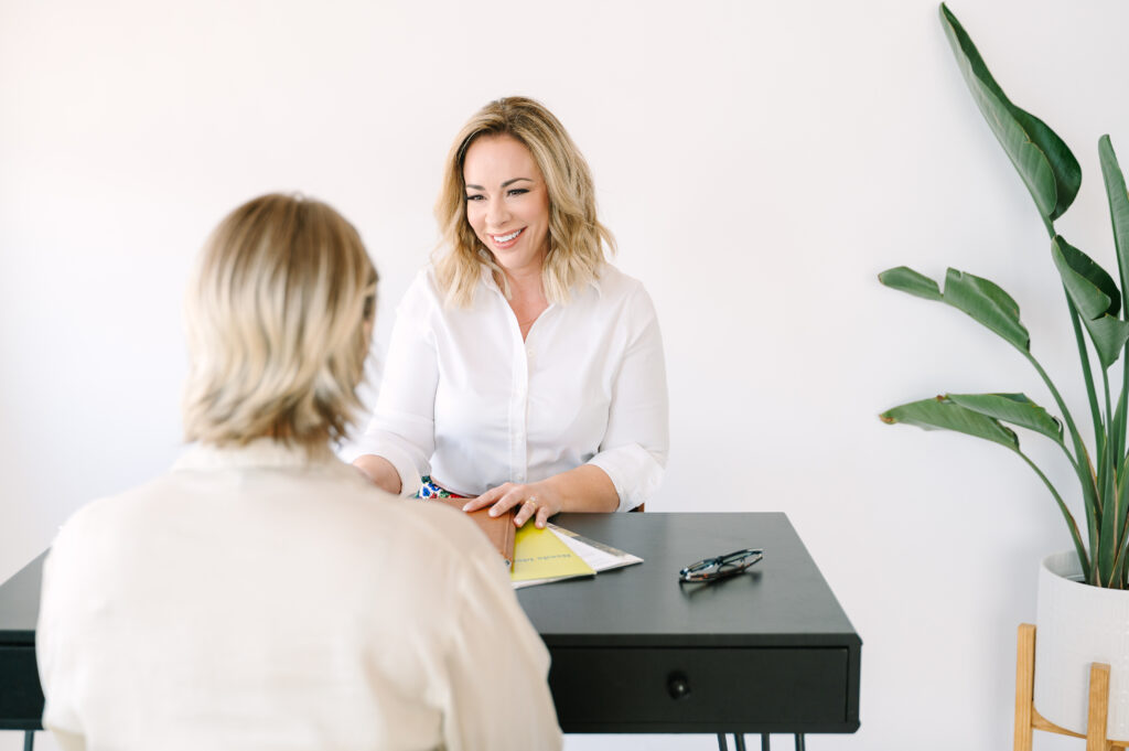 Strategic brand photos with model coaching a client by table